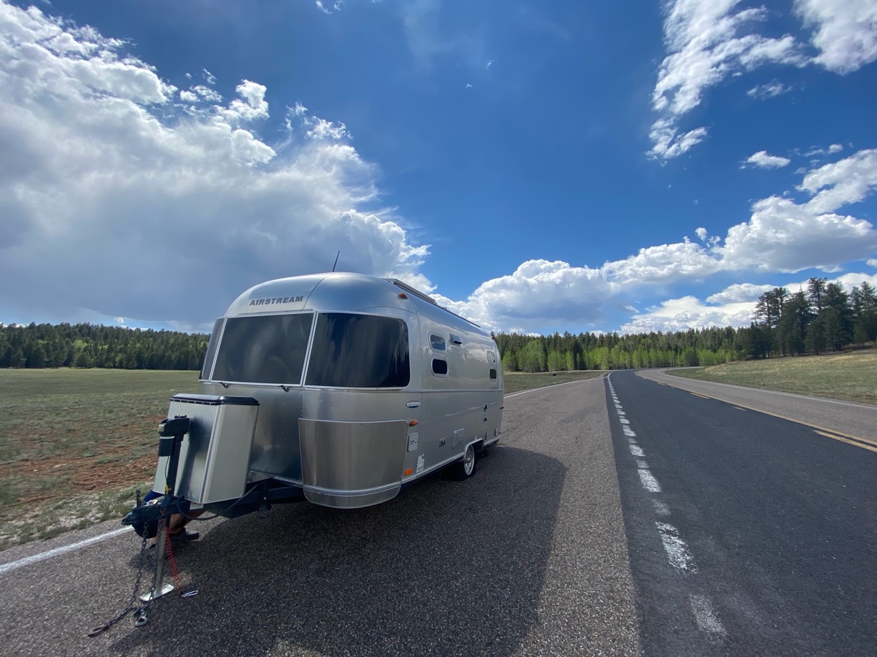 Silver Airstream parked in a roadside pull-off beneath large clouds on the drive toward the Grand Canyon’s North Rim.